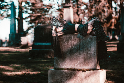 Gothic girl laying on a gravestone