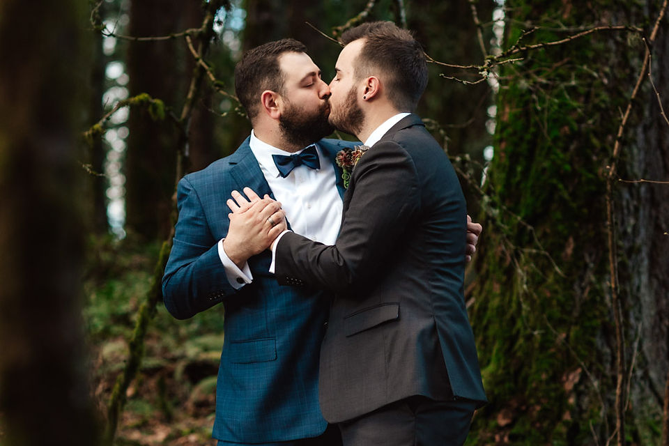 Grooms kiss on wedding day in forest setting