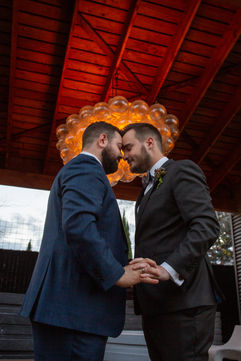 Grooms snuggle and pose for wedding photographer in front of nursery wedding venue