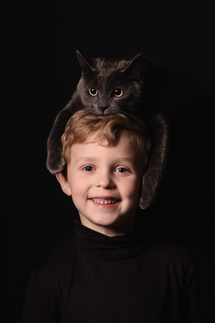Studio lit low key portrait with cat on boys head