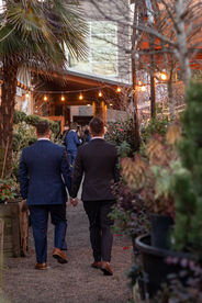 Grooms hold hands and enter Portland wedding venue