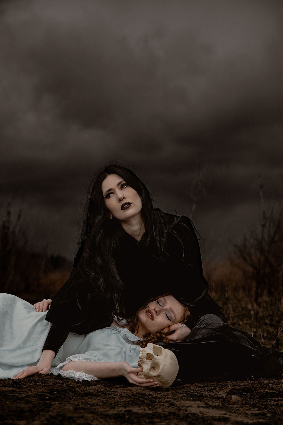 Woman holding another girl playing dead with skull