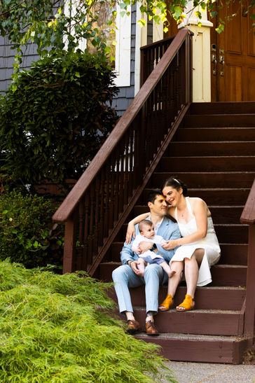 Bride and groom in traditional attire hold toddler on stairs at wedding