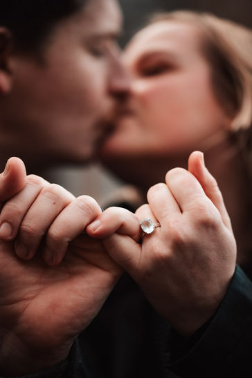 Couple kisses and crosses ring fingers