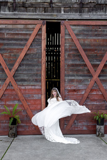 Wild bride throws dress in front of red barn doors