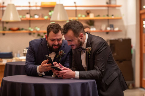 Couple pause from wedding to look at cell phones and laugh
