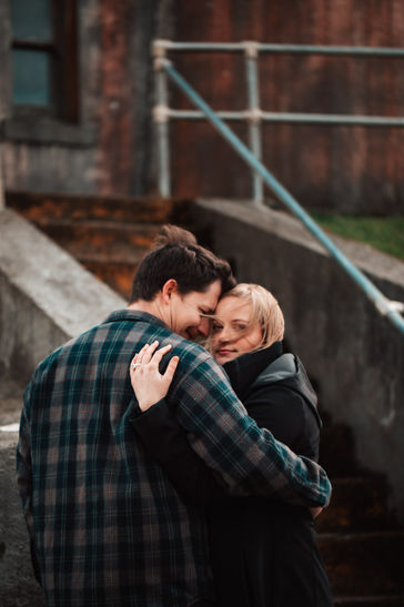 Windswept couple in front of abandoned lighthouse on Oregon coast