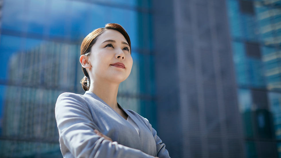Confident woman in a gray suit stands with crossed arms in front of modern glass buildings. Logo reads "a to z Consultancy Solutions."