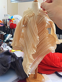 Daphne Valente fashion designer plise, pleated, sculptural fashion design, Daphne Valente playing with her miniature dress stand, she lovingly drapes her pleated fabrics, creating free flowing, elegant, timeless garments.