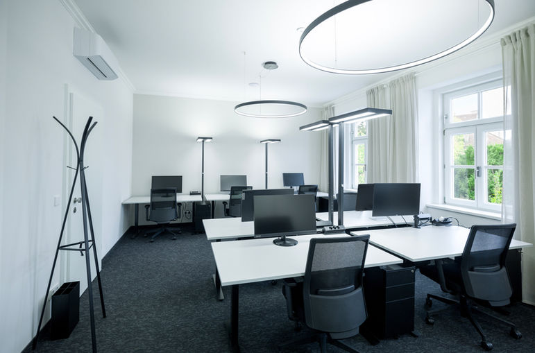 Fix Membership Bereich im 1. Obergeschoss von Sissi Works Coworking Space Wien. Höhenvertsellbare Schreibtische, Arbeitslampen, Bürostühle, dunkler Teppichboden