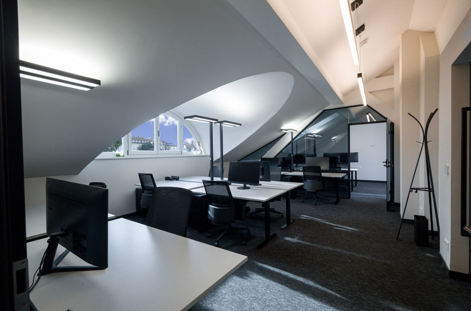 Fix Membership Bereich im Dachgeschoss von Sissi Works Coworking Space Wien. Höhenvertsellbare Schreibtische, Arbeitslampen, Bürostühle, dunkler Teppichboden