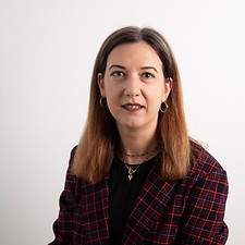 A woman in a blazer poses against a white background. Knowlo Global.
