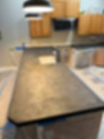 Kitchen countertops during surface preparation for a custom black concrete countertop installation.