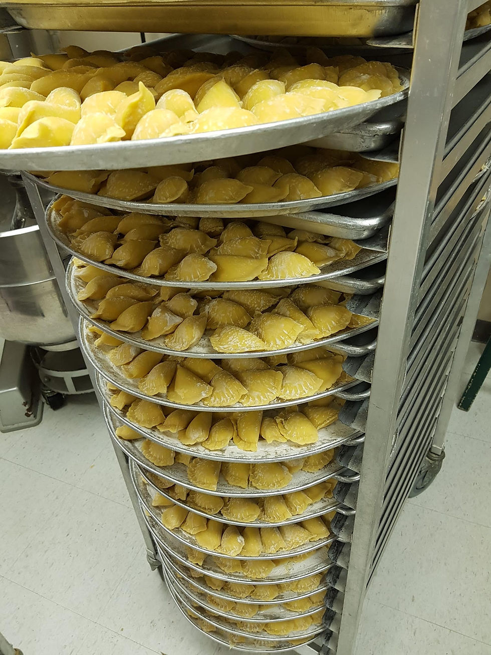 Trays with raw pierogi on a cart.