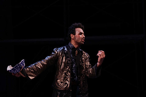 Samuel Colina as Don Pedro, holding a blue mask, in the middle of a monologue. Wearing a dirty gold and blue costume.