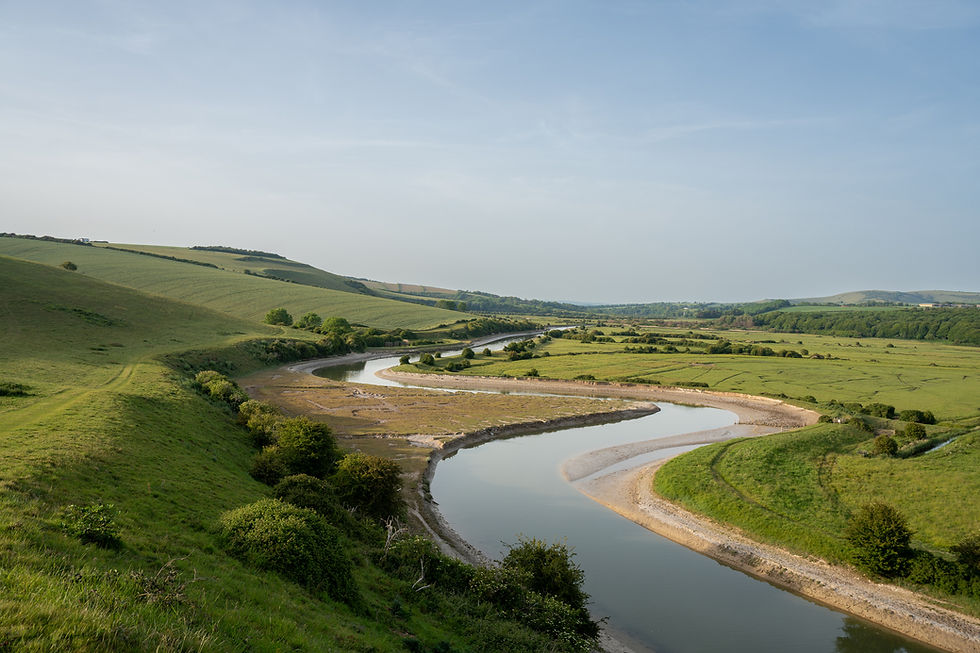 Winding river through green rolling hills under a clear blue sky, a calm rural landscape with no people visible