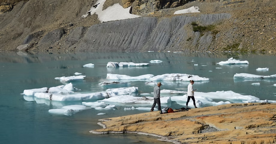 Two people walking along the shore of Grinnell Lake