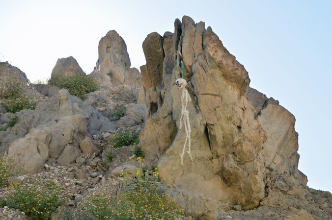 plastic skeleton hanging from a rope in the skeleton canyon walls