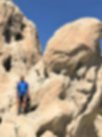 Hiker standing in wind and rain eroded sedimentary rocks along Indio Hills Badland Loop Trail