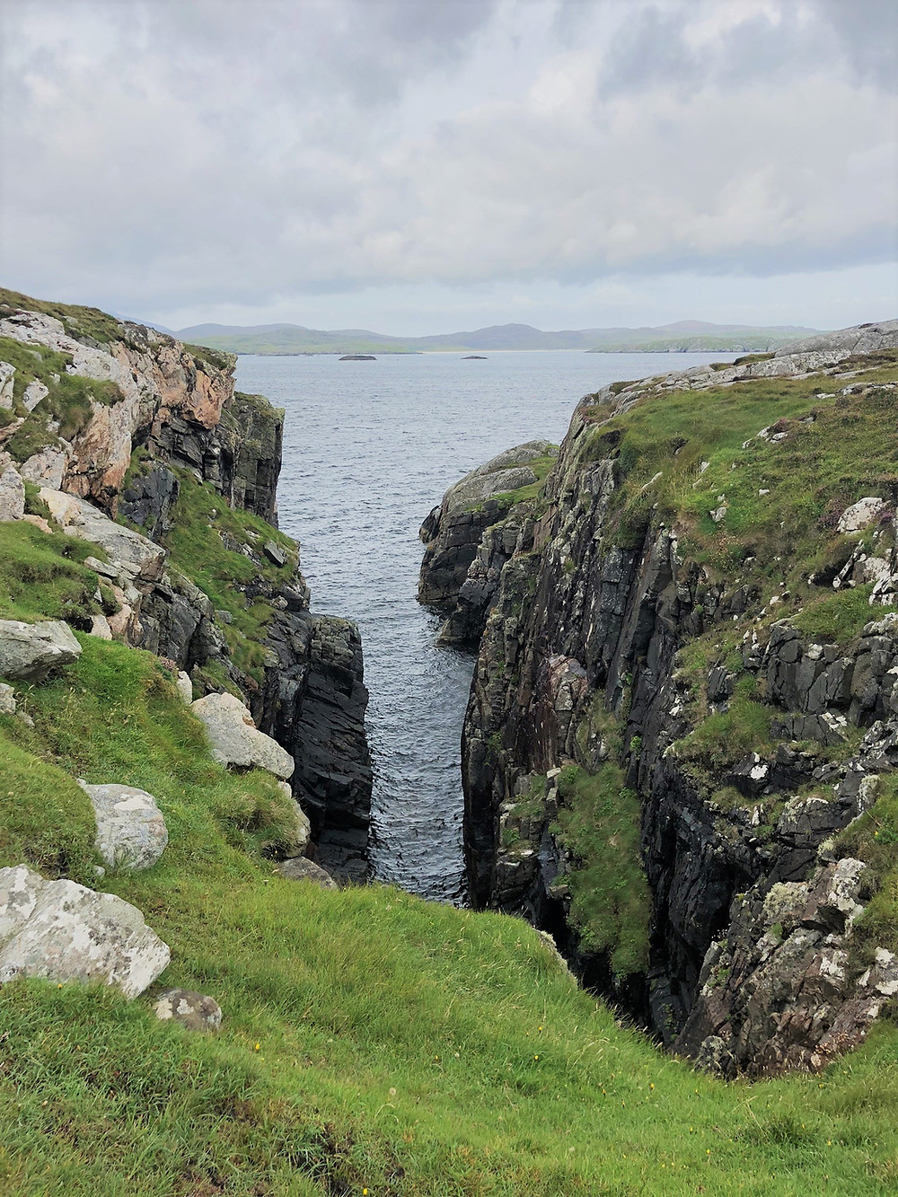 Rocky ledges and sea cliffs rose 50 feet above the water of Loch Roag on Great Bernera Loop hike on the