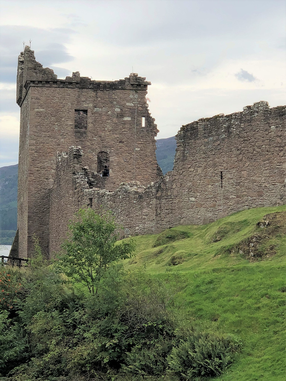 Ruins of Urquhart castle towers and walls sits on the banks of Loch Ness