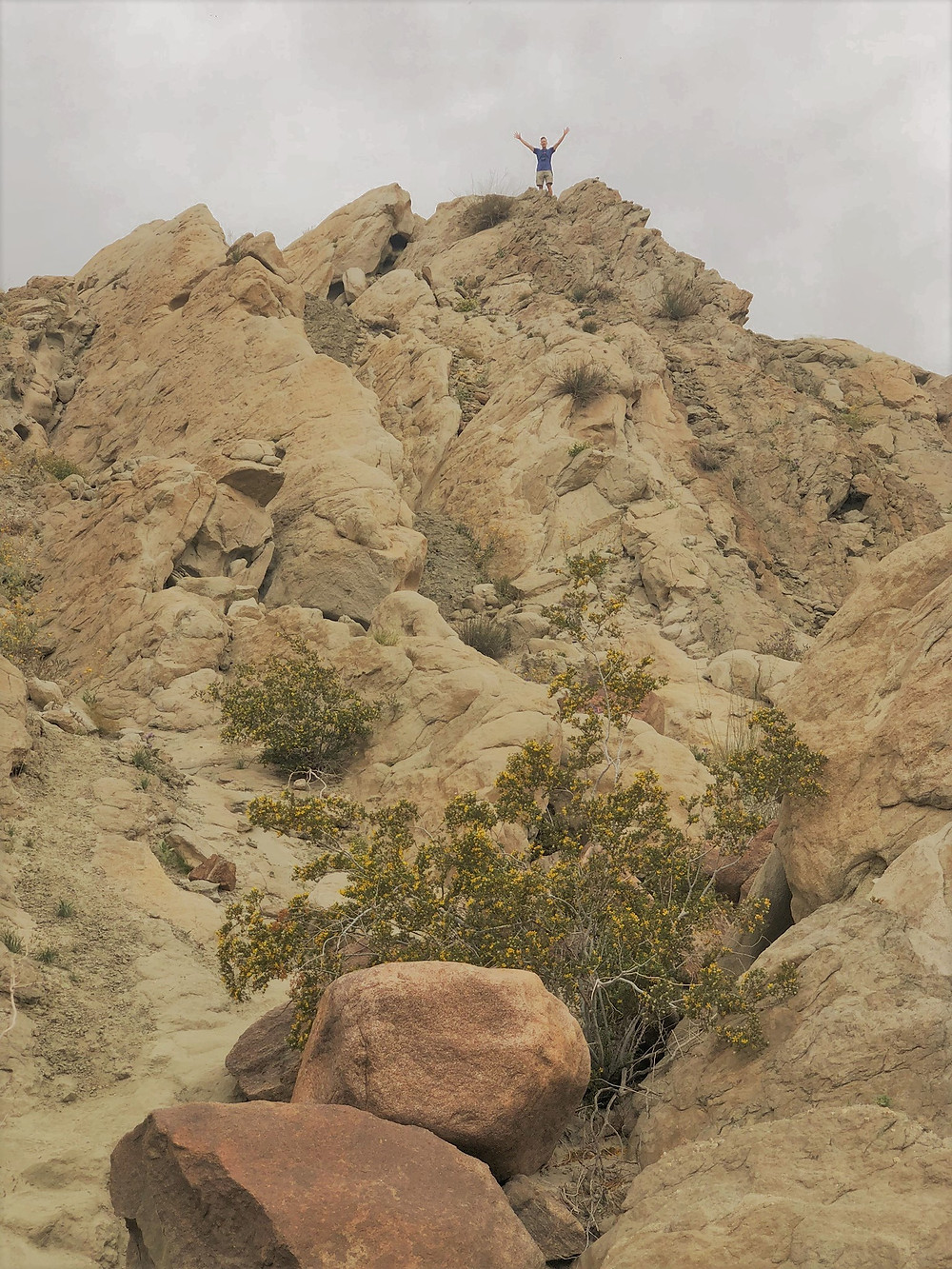 Hiker standing in wind and rain eroded sedimentary rocks along Indio Hills Badland Loop Trail