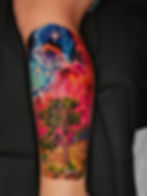 Vibrant nebula and Joshua tree tattoo on an arm.