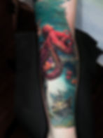 Red octopus and sunken ship tattoo on a forearm