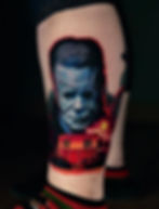 Michael Myers tattoo on a leg featuring a Michael's family house. Done in color realism style