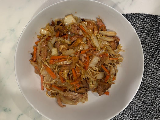 Chicken yakisoba with homemade noodles, cabbage, carrot strips, and shiitake mushrooms in a white bowl.