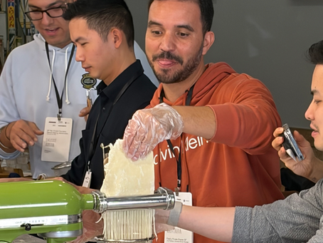 Corporate team members making fresh ramen noodles together during a hands-on team building activity in San Francisco.