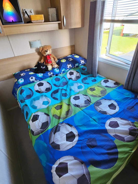 A view of a double bed with themed bedding and toys on, this example shows generic football