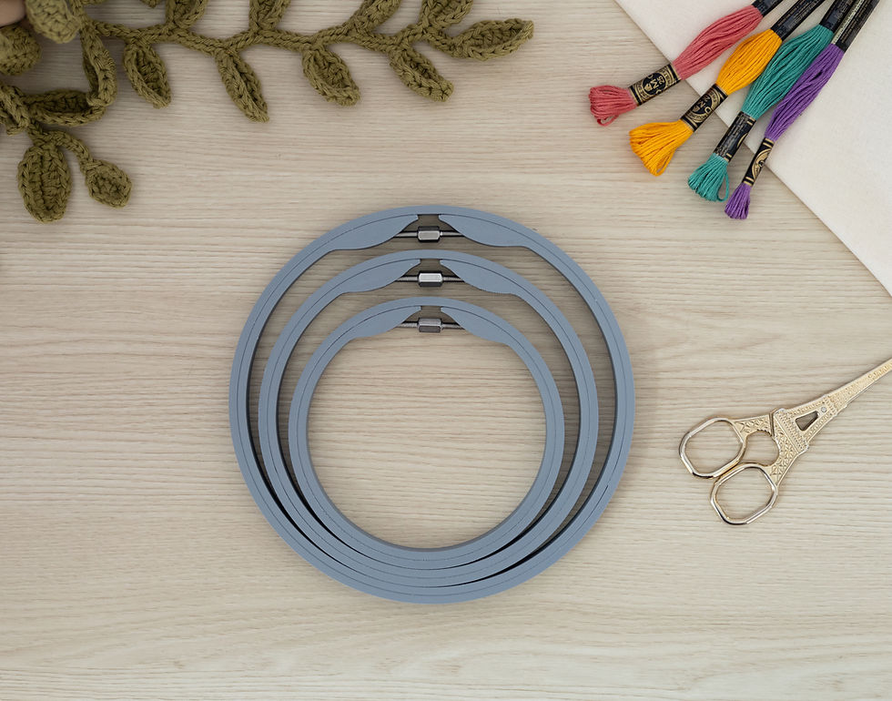 Set of three Matte Ash Grey seamless round embroidery hoops on wood background, styled with fabric, thread, and scissors