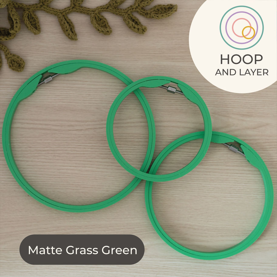 Set of three Matte Grass Green round embroidery hoops on light wood background, styled with a green crochet plant
