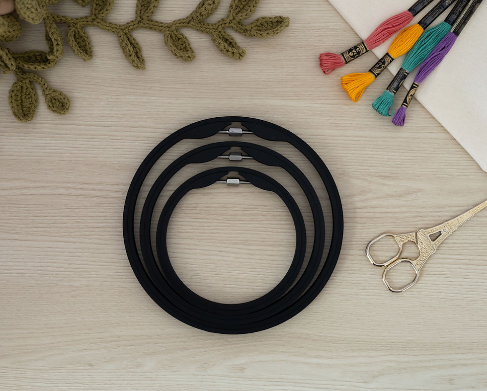 Set of three Matte Charcoal seamless round embroidery hoops on wood background, styled with fabric, thread, and scissors