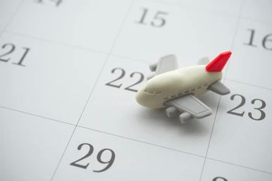 A small toy airplane placed on a calendar, symbolizing scheduled nanny paid time off and planned vacations.