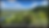 Panoramic bluff view over a lush river floodplain and forested hills under a blue, cloud-filled sky.