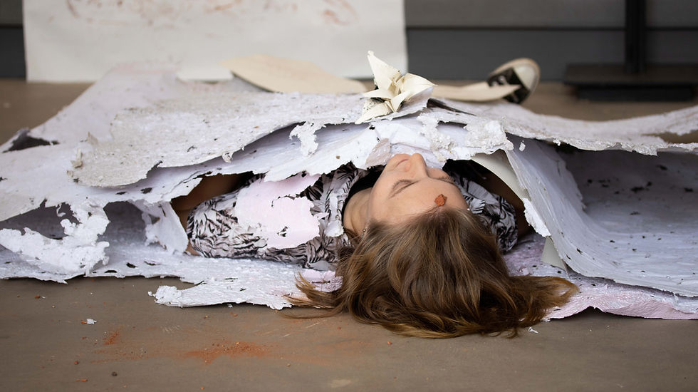 Person lying on floor, covered with paper.