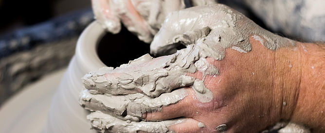 Hand shaping clay on the wheel