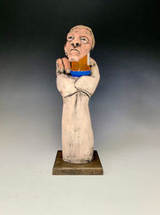 clay sculpture of human head on pill bottle being held up by a hand.