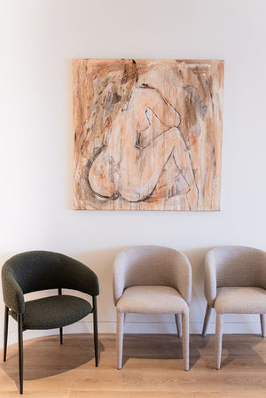 Three chairs under abstract nude painting on wall in a medical reception area.