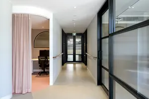 Modern hallway with glass partitions and a pink curtain.