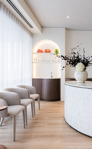 Modern, minimalist medical interior with chairs, tiled reception desk and arched display area.