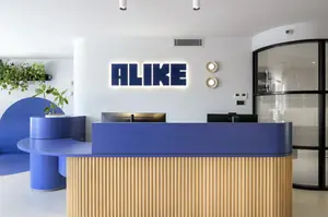Modern healthcare reception area with bold blue accents and natural timber to curved custom reception desk.