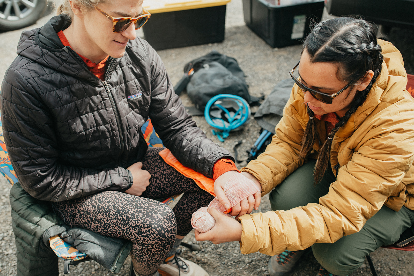 Two course participants practice padding and splinting a forearm during an outdoor first-aid exercise