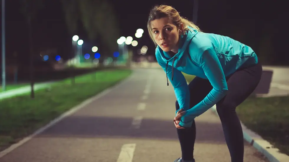 a woman during a night run catching a breath