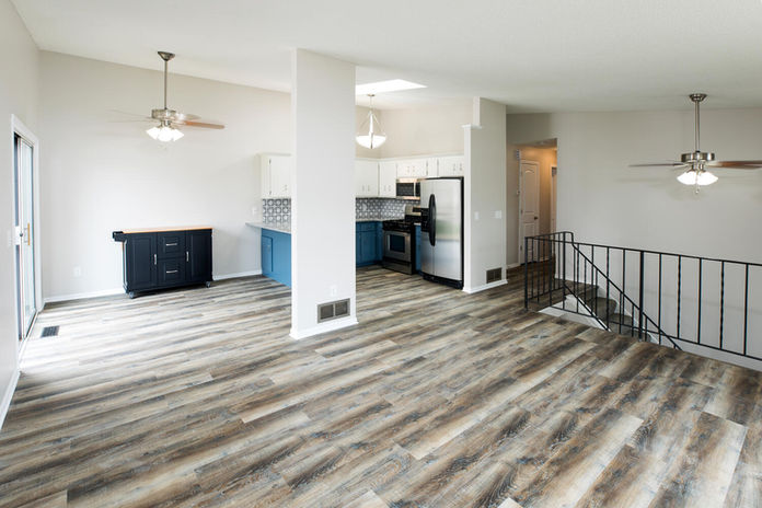 Open concept living space with kitchen, blue cabinets, and stainless steel appliances.