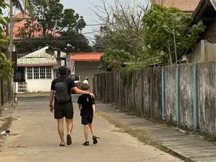 Vater und Sohn spazieren durch eine ruhige Strasse in Sri Lanka