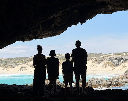 family-stand-in-cave-overlooking-secret-beach