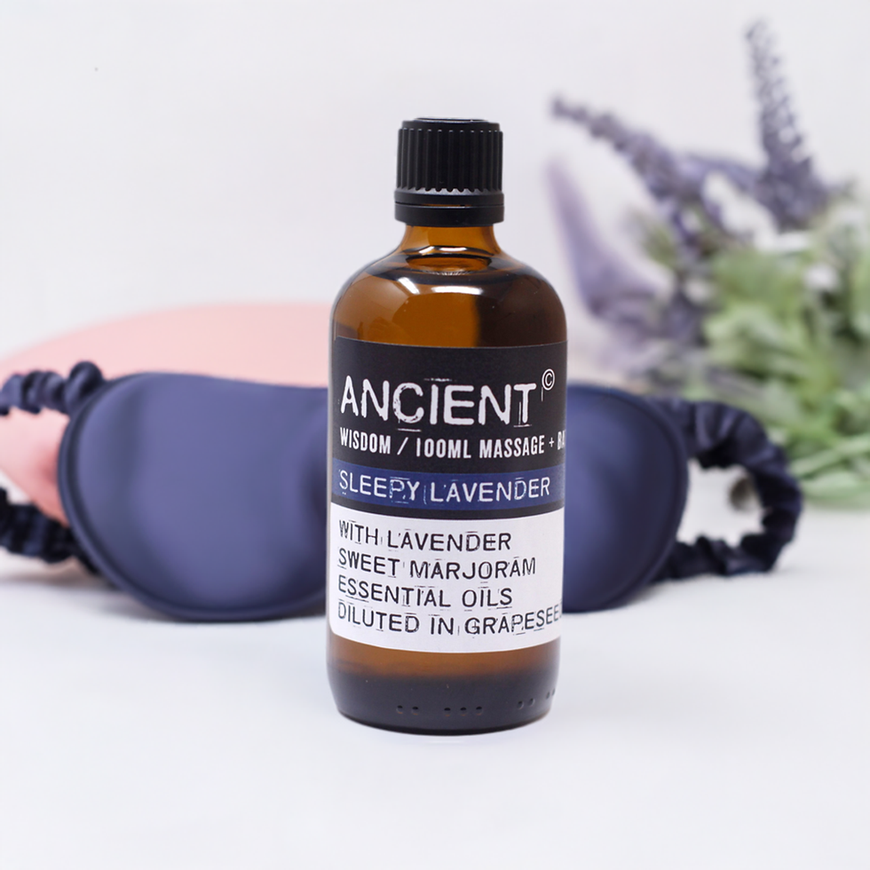 Bottle of relaxing lavender massage oil with cut lavender and sleeping mask in background